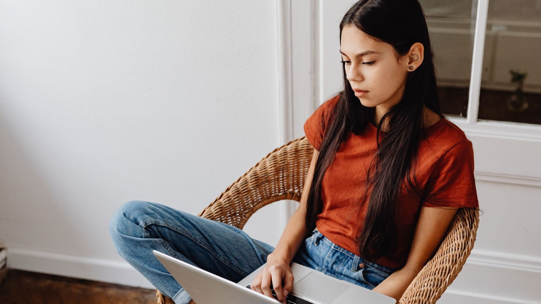 woman sitting on a wicker chair working on her laptop