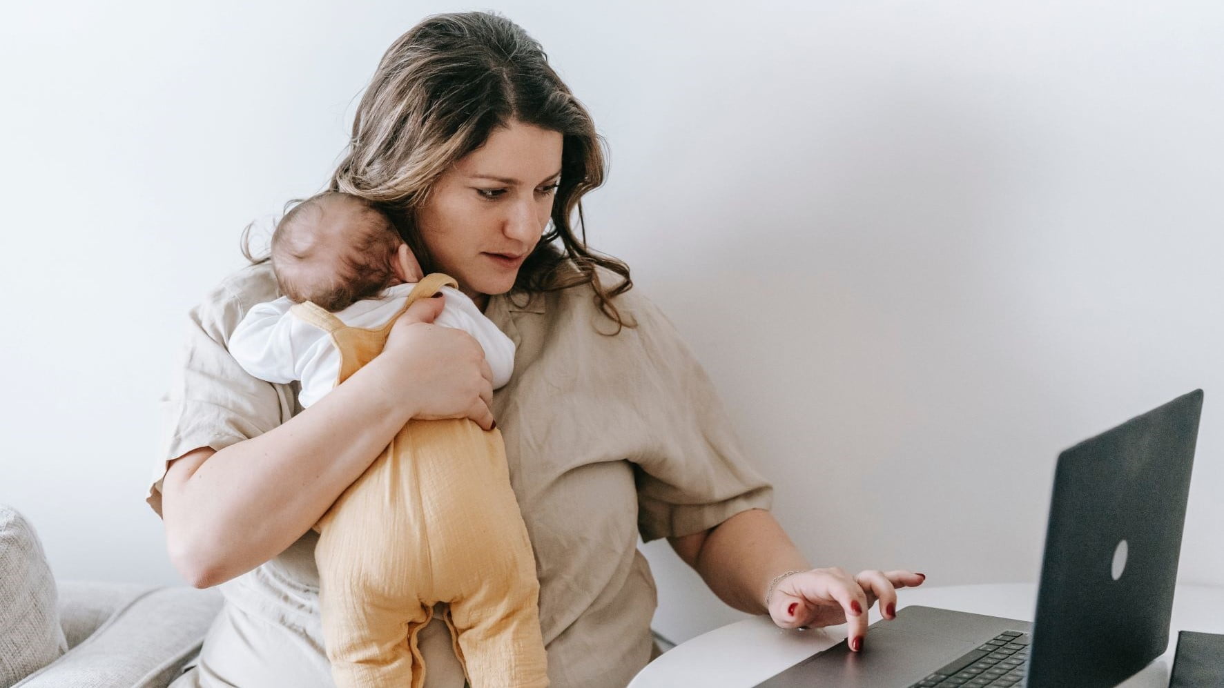 freelancer holding her baby while she works